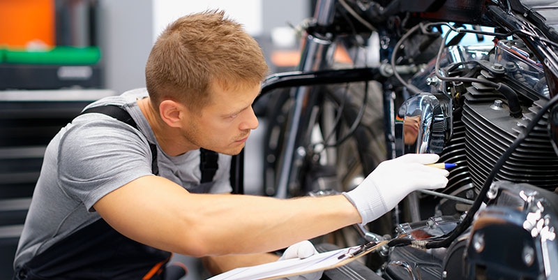 Hombre reparando moto: servicio de peritaciones 24h en el seguro de moto